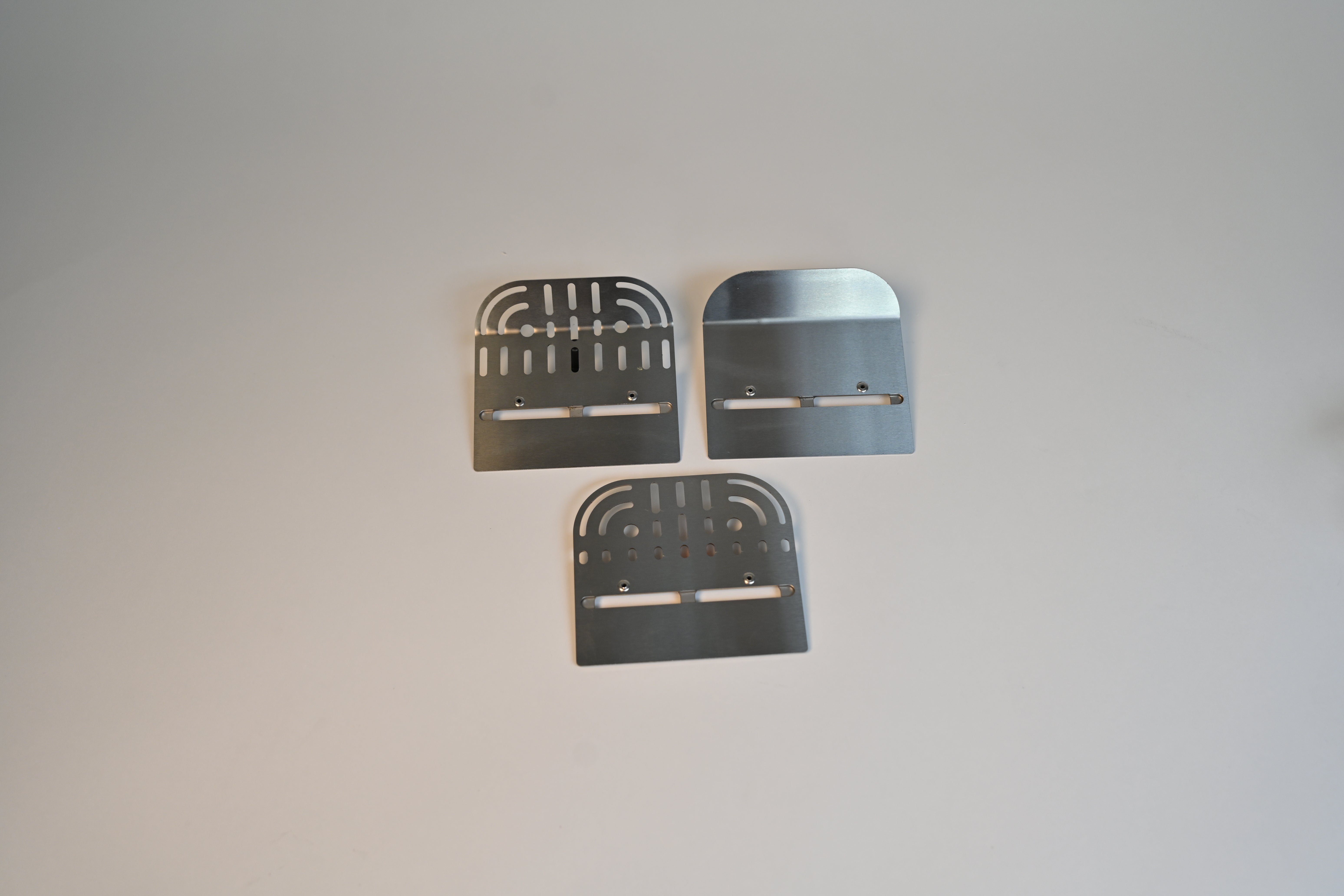 Three metal brackets on a light gray background